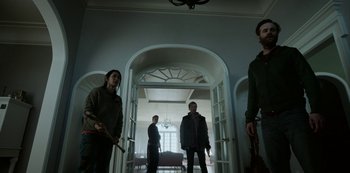 Movie still from “Black Summer” (2019), created by John Hyams – A group of people standing inside of a room; Wide shot, Low angle