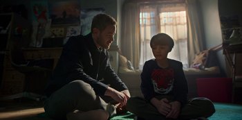 Movie still from “Locke & Key” (2020), created by Carlton Cuse – A man sitting next to a young boy in a room; Medium shot, Over the shoulder angle