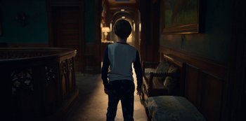 Movie still from “Locke & Key” (2020), created by Carlton Cuse – A young boy standing in a dark hallway; Wide shot, Over the shoulder angle
