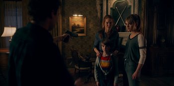 Movie still from “Locke & Key” (2020), created by Carlton Cuse – A group of people in a living room with a gun; Medium shot, Over the shoulder angle