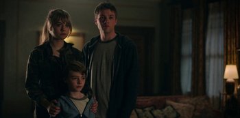 Movie still from “Locke & Key” (2020), created by Carlton Cuse – A group of people standing next to each other in a living room; Medium shot, Low angle