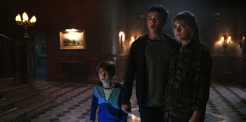 Movie still from “Locke & Key” (2020), created by Carlton Cuse – A group of people standing in a dark room holding hands; Medium shot, High angle