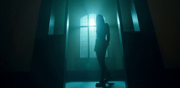 Movie still from “Locke & Key” (2020), created by Carlton Cuse – A person standing in a room with a light shining through the window; Wide shot, Low angle