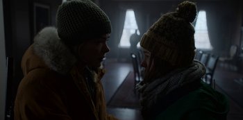 Movie still from “Black Summer” (2019), created by John Hyams – Two people are talking in a dark room; Medium shot, Over the shoulder angle