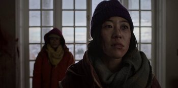Movie still from “Black Summer” (2019), created by John Hyams – Two women wearing winter clothing in front of a window; Close Up shot, Low angle