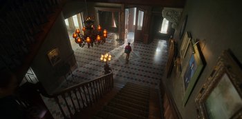 Movie still from “Locke & Key” (2020), created by Carlton Cuse – A man walking down a staircase in a large room; Extreme Wide shot, High angle