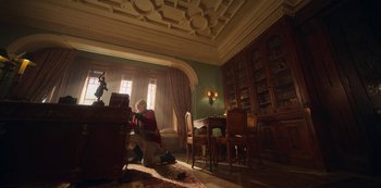 Movie still from “Locke & Key” (2020), created by Carlton Cuse – A man sitting at a desk in a room with a lot of furniture; Wide shot, Low angle