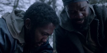 Movie still from “Black Summer” (2019), created by John Hyams – Two men are standing in the woods looking at each other; Close Up shot, Over the shoulder angle