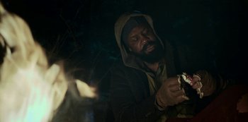 Movie still from “Black Summer” (2019), created by John Hyams – A man holding something while standing in front of a fire; Close Up shot, Over the shoulder angle