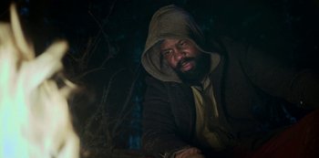Movie still from “Black Summer” (2019), created by John Hyams – A man with a beard wearing a hooded jacket; Medium shot, Low angle