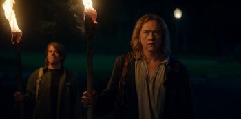 Movie still from “Locke & Key” (2020), created by Carlton Cuse – A man holding a burning candle in a dark place; Medium shot, Over the shoulder angle