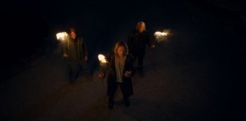 Movie still from “Locke & Key” (2020), created by Carlton Cuse – A group of people walking in the dark with torches; Wide shot, High angle