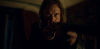 Movie still from “Locke & Key” (2020), created by Carlton Cuse – A man holding a gun in a dark room; Close Up shot, Over the shoulder angle