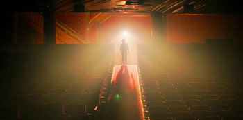 Movie still from “Locke & Key” (2020), created by Carlton Cuse – A man standing in a theater with a light shining on him; Extreme Wide shot, Low angle