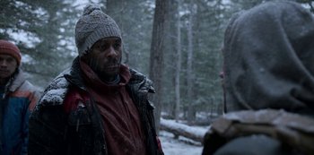 Movie still from “Black Summer” (2019), created by John Hyams – A man wearing a winter hat and jacket talking to another man in the woods; Close Up shot, Over the shoulder angle