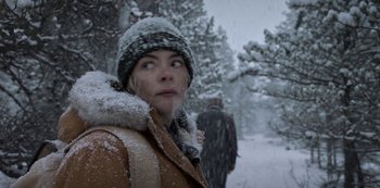 Movie still from “Black Summer” (2019), created by John Hyams – A woman standing in the snow looking up at the sky; Close Up shot, Over the shoulder angle