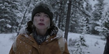 Movie still from “Black Summer” (2019), created by John Hyams – A woman in a brown coat and a black hat in the snow; Close Up shot, Over the shoulder angle