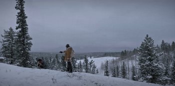 Movie still from “Black Summer” (2019), created by John Hyams – A man standing on top of a snow covered slope; Extreme Wide shot, Low angle
