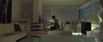 Movie still from “Blackhat” (2015), directed by Michael Mann – A man sitting in front of a computer in a living room; Wide shot, High angle