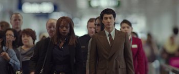 Movie still from “Blackhat” (2015), directed by Michael Mann – A group of people in suits walking in a crowd; Medium shot, Low angle