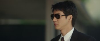 Movie still from “Blackhat” (2015), directed by Michael Mann – A man in a suit and sunglasses looking to his left; Close Up shot, Low angle