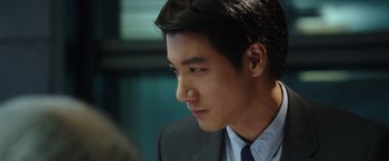 Movie still from “Blackhat” (2015), directed by Michael Mann – A man in a suit and tie looking to his left; Close Up shot, Over the shoulder angle