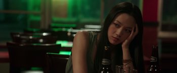 Movie still from “Blackhat” (2015), directed by Michael Mann – A woman sitting at a table with a bottle of beer; Close Up shot, Over the shoulder angle