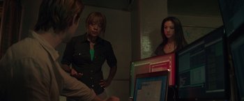 Movie still from “Blackhat” (2015), directed by Michael Mann – A group of people standing in a room with a laptop computer; Medium shot, Over the shoulder angle