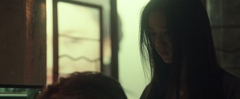 Movie still from “Blackhat” (2015), directed by Michael Mann – A woman standing next to another woman in a room; Close Up shot, Over the shoulder angle