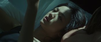 Movie still from “Blackhat” (2015), directed by Michael Mann – A woman laying on the ground looking at the camera; Close Up shot, Low angle