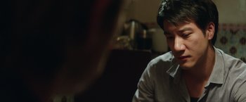 Movie still from “Blackhat” (2015), directed by Michael Mann – A man sitting in front of a table; Close Up shot, Over the shoulder angle