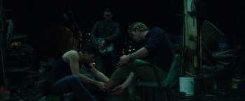 Movie still from “Blackhat” (2015), directed by Michael Mann – A group of men sitting around each other on a chair; Medium shot, High angle