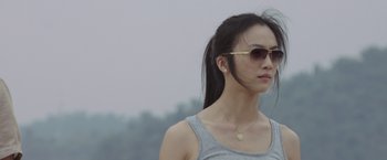 Movie still from “Blackhat” (2015), directed by Michael Mann – A woman wearing a gray tank top and a pair of sunglasses; Close Up shot, Low angle
