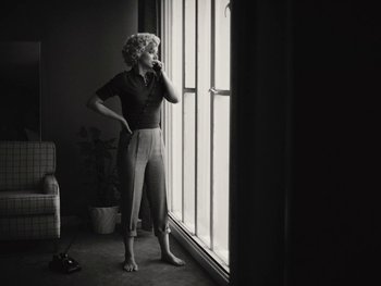 Movie still from “Blonde” (2022), directed by Andrew Dominik – A black and white photo of a woman standing in front of a window; Medium shot, Low angle
