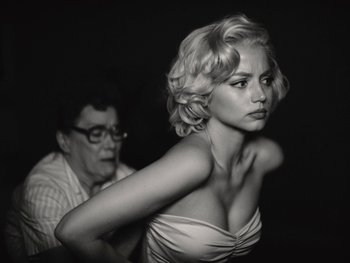 Movie still from “Blonde” (2022), directed by Andrew Dominik – A woman in a white dress and a man in glasses; Close Up shot, Low angle