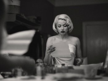 Movie still from “Blonde” (2022), directed by Andrew Dominik – A black and white photo of a woman looking at a piece of paper; Medium shot, Low angle