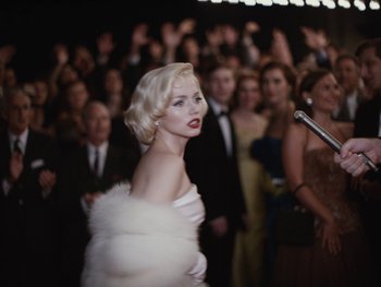 Movie still from “Blonde” (2022), directed by Andrew Dominik – A woman in a white dress and a white fur coat; Medium shot, Over the shoulder angle