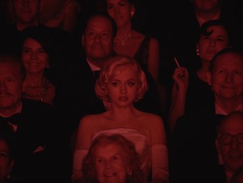Movie still from “Blonde” (2022), directed by Andrew Dominik – A group of people sitting in a dark room; Medium shot, Over the shoulder angle