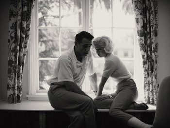 Movie still from “Blonde” (2022), directed by Andrew Dominik – A man and a woman sitting in front of a window; Medium shot, Low angle