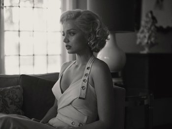 Movie still from “Blonde” (2022), directed by Andrew Dominik – A black and white photo of a woman sitting on a couch; Medium shot, Low angle