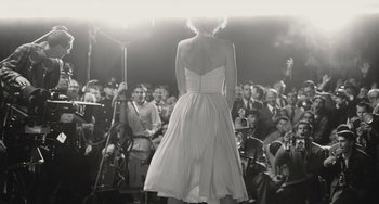 Movie still from “Blonde” (2022), directed by Andrew Dominik – A black and white photo of a woman in a white dress; Wide shot, Over the shoulder angle