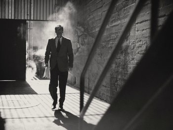 Movie still from “Blonde” (2022), directed by Andrew Dominik – A black and white photo of a man in a suit and tie; Wide shot, Low angle