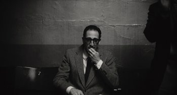 Movie still from “Blonde” (2022), directed by Andrew Dominik – A black and white photo of a man smoking a cigarette; Medium shot, High angle