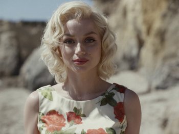 Movie still from “Blonde” (2022), directed by Andrew Dominik – A woman with blonde hair wearing a floral dress; Close Up shot, Over the shoulder angle