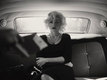 Movie still from “Blonde” (2022), directed by Andrew Dominik – A woman sitting in the back seat of a car; Medium shot, Low angle