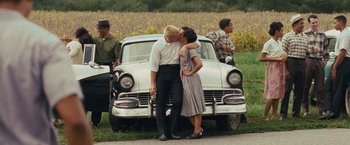 Movie still from “Loving” (2016), directed by Jeff Nichols – A man and a woman kissing in front of a car; Wide shot, Over the shoulder angle