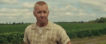 Movie still from “Loving” (2016), directed by Jeff Nichols – A man in a checkered shirt standing in front of a corn field; Close Up shot, Low angle