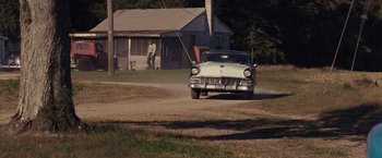 Movie still from “Loving” (2016), directed by Jeff Nichols – An old white car driving down a dirt road past a house; Wide shot, Over the shoulder angle