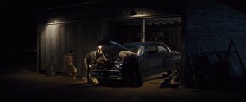 Movie still from “Loving” (2016), directed by Jeff Nichols – A couple of men working on a car in a garage; Wide shot, Low angle