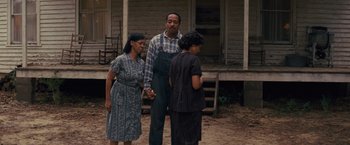 Movie still from “Loving” (2016), directed by Jeff Nichols – A man and two women standing in front of a house; Medium shot, Over the shoulder angle
